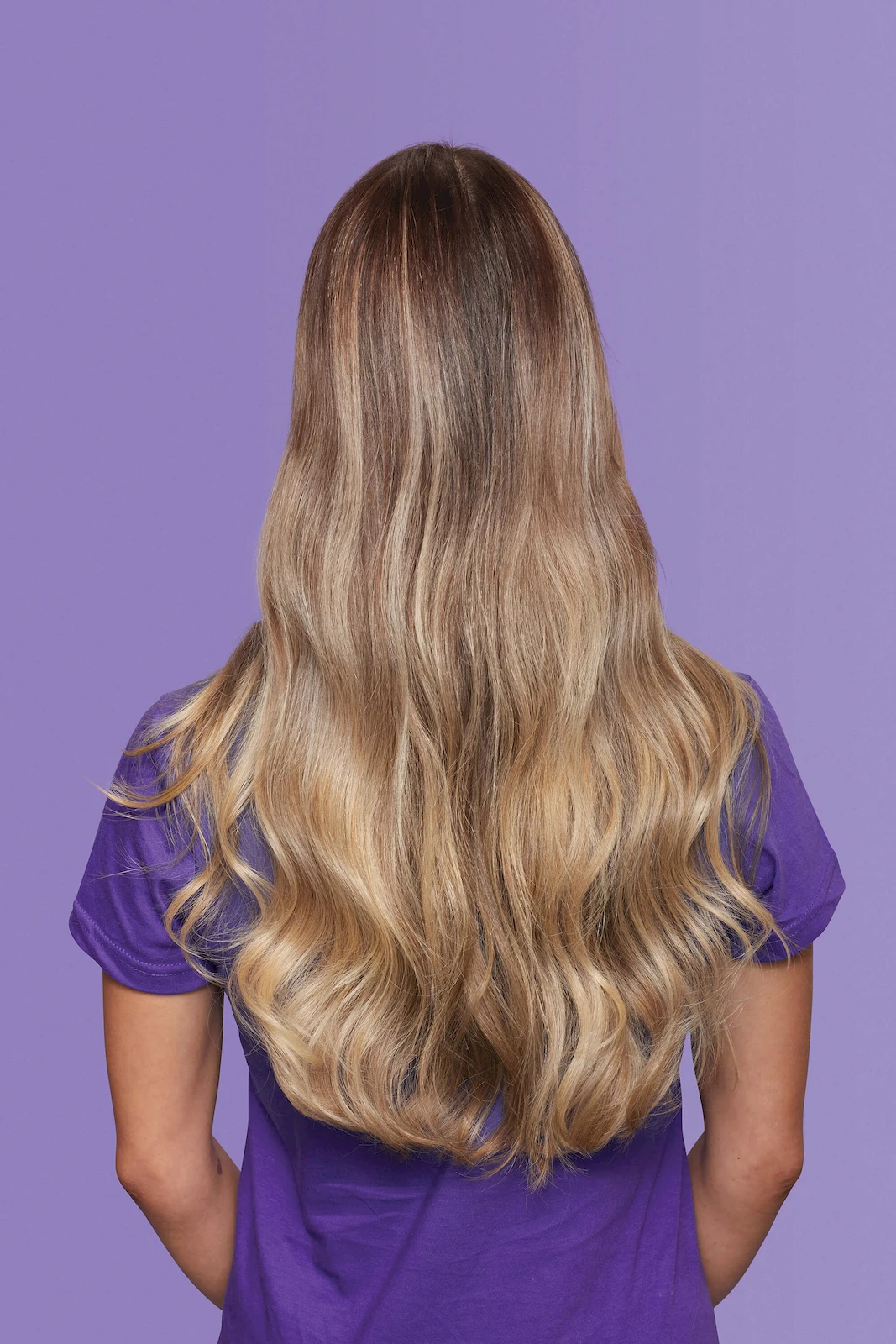 Kobieta prezentująca lśniące, falowane blond włosy