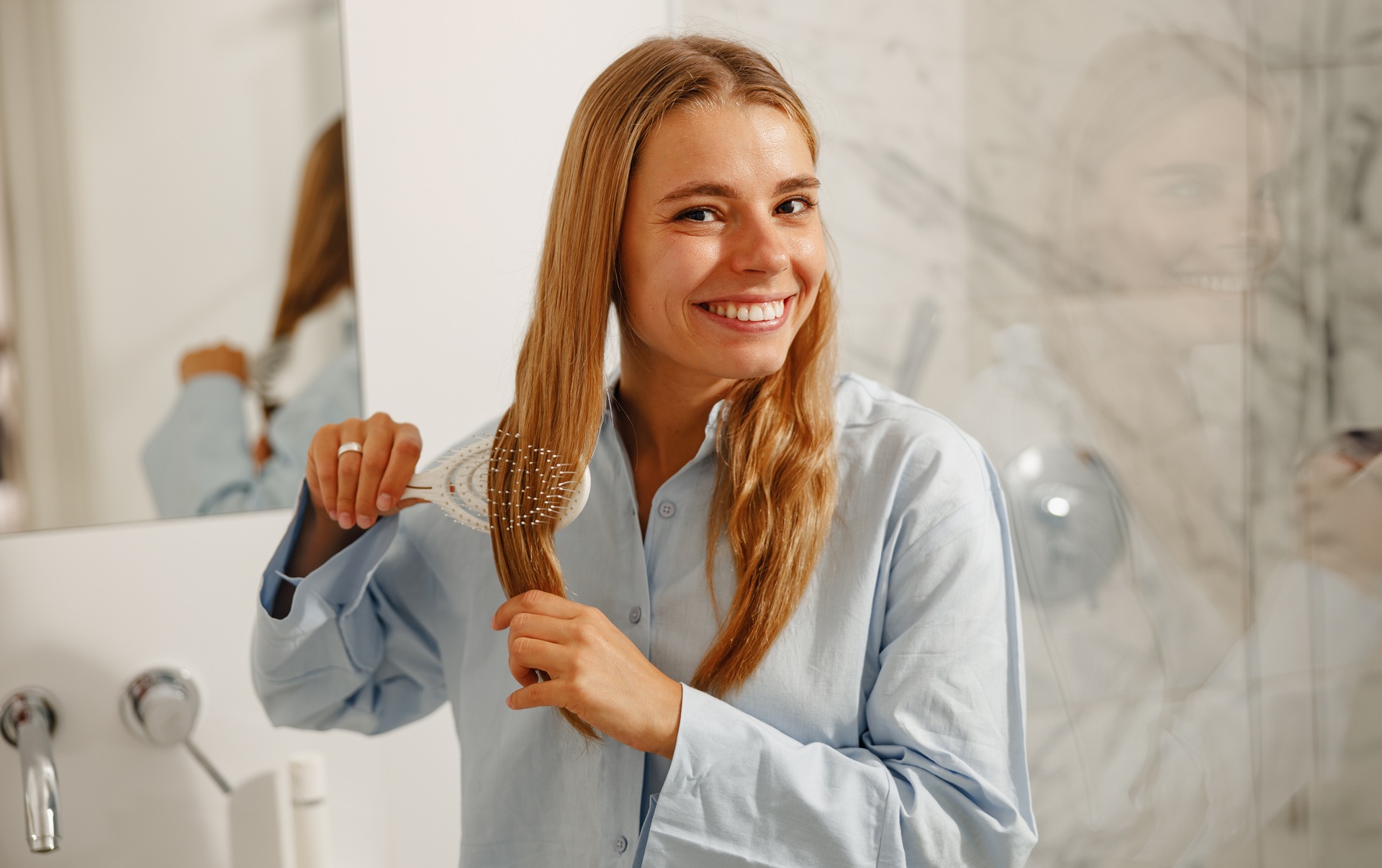 Młoda kobieta rozczesująca blond włosy w łazience